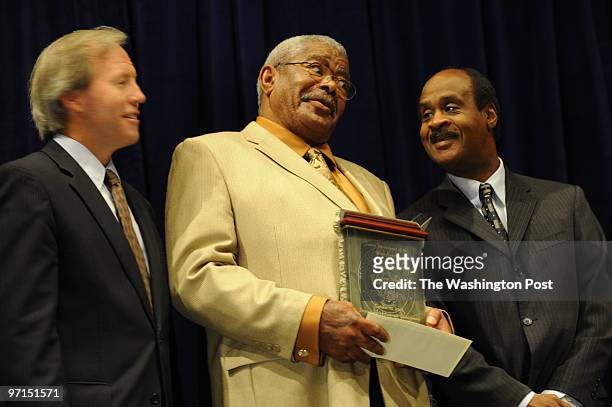 Flanked by Montgomery County Council President Phil Andrews, left, and County Executive Isiah Leggett, Anthony Bruce is surprised at the $1,000 check...