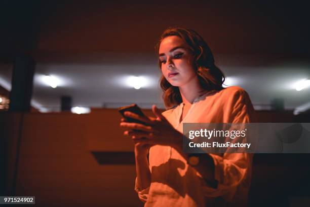 businesswoman with a mobile phone standing outdoors - stalker person stock pictures, royalty-free photos & images