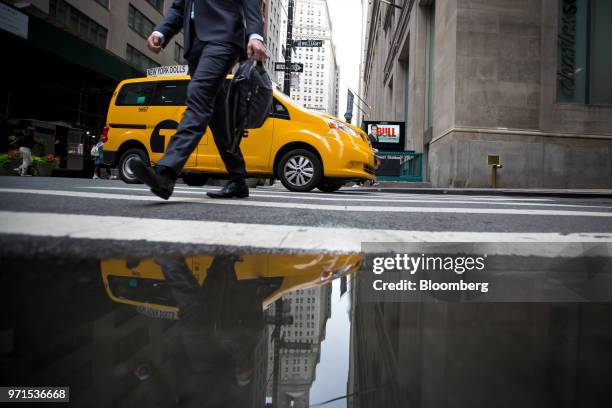 Man walks along Wall Street as a taxi turns a corner near the New York Stock Exchange in New York, U.S., on Monday, June 11, 2018. U.S. Equities...