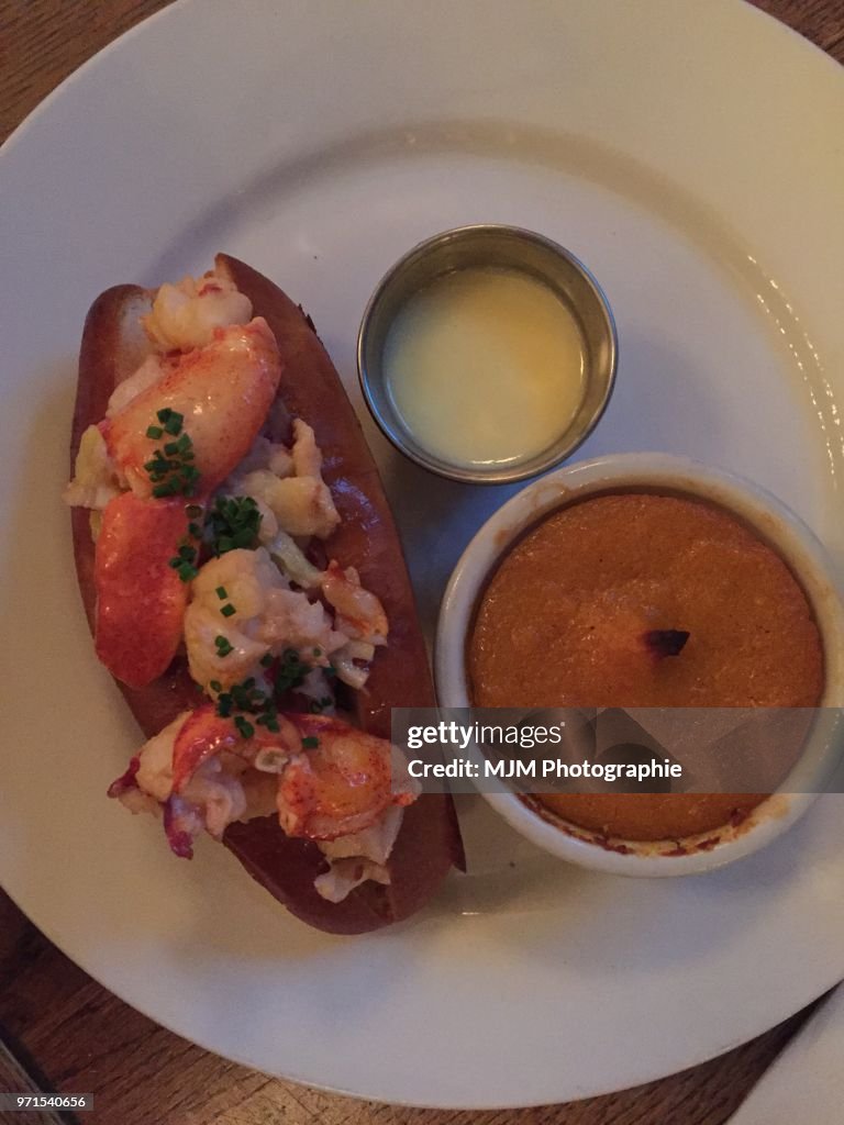 Lobster roll with side root vegetable soufflé on a white plate