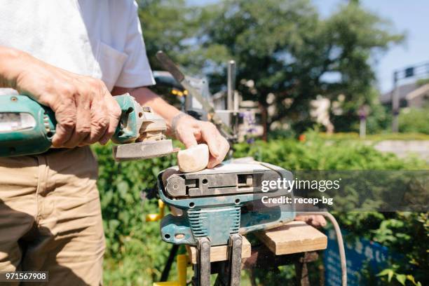 close-up photo of hands of senior man while making craft from wood - park man made space stock pictures, royalty-free photos & images