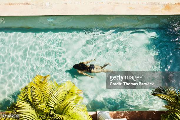 Overhead view of woman swimming underwater in outdoor pool at spa