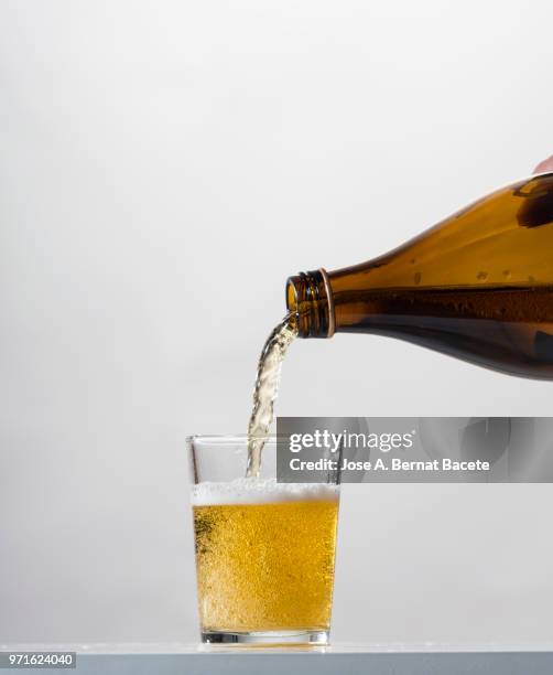 pouring glass of beer from bottle on a white background. - lager stock pictures, royalty-free photos & images