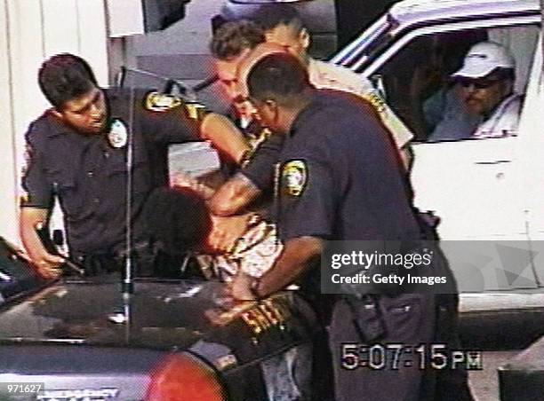 An unidentified man looks on as Inglewood police officers arrest 16-year-old Donovan Jackson on July 8, 2002 in Inglewood, California. Jackson was...