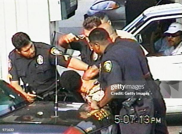 An Inglewood police officer raises his fist while other officers restrain 16-year-old Donovan Jackson on July 8, 2002 in Inglewood, California....