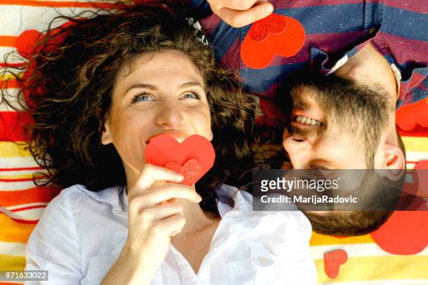 porträt von süß süßes paar liegen kopf an kopf auf dem boden mit kleinen roten herzen um - marijaradovic stock-fotos und bilder