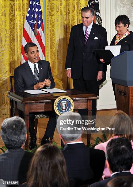 White House. Pictured, President Obama smiles as he prepares to sign a memorandum in the East Room. With him on the right are the new Secretary of...