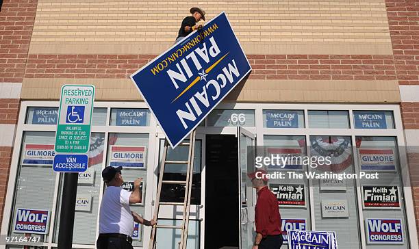 Oliver "O.P." Ditch of Woodbridge, Virginia, steadies the ladder as Conrad Holtslag of Gainesville, Virginia, replaces the sign at McCain-Palin...