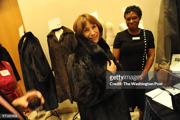 The French Embassy Lauren Howard, of Washington, D.C., tries on a full length mink coat for size at a silent auction and fashion show at the French...