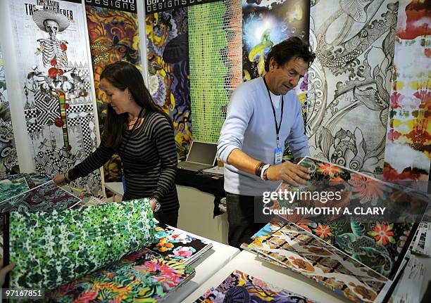 An exhibitor from Garreau Designs shows off some fabrics to member of the trade during the Direction by Indigo International Exhibition of Creative...