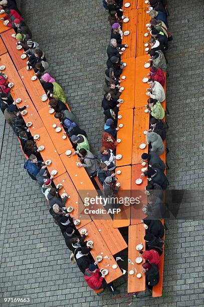 Greenpease activists sit on benches and tables and eat genetically modified organism free potato soup during a protest against genetically...