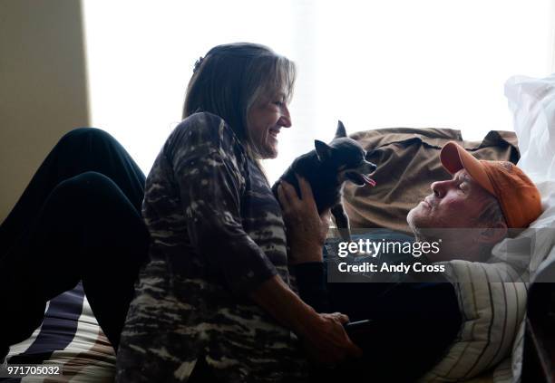 Deb Ploetz, left, has a moment with her husband, Greg Ploetz, while he lays in bed holding their dog, Butter Wednesday at the Applewood Our House, a...