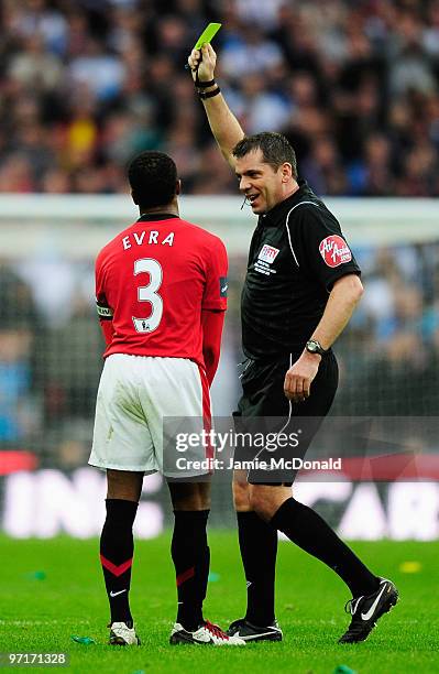 Patrice Evra of Manchester United is booked by referee Phil Dowd during the Carling Cup Final between Aston Villa and Manchester United at Wembley...