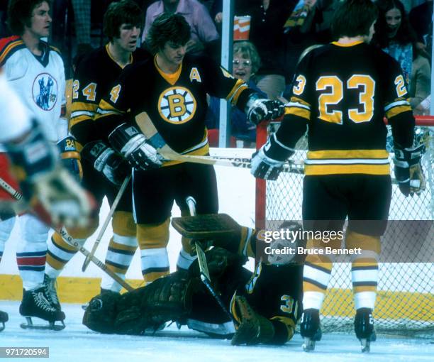 Goalie Ross Brooks of the Boston Bruins makes the save as he gets help from teammates Bobby Orr, Terry O'Reilly and Al Sims as Ed Gilbert of the...