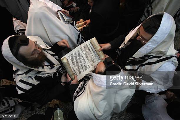 Ultra-orthodox Jews follow the reading of the Scroll of Esther during Purim festival prayers at the Vishnitz Chassidic synagogue on February 28, 2010...