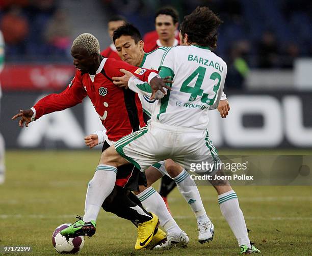 Arouna Kone of Hannover and Andrea Barzagli and Makoto Hasebe of Wolfsburg compete for the ball during the Bundesliga match between Hannover 96 and...