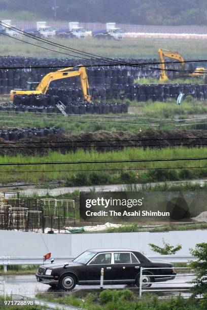 Car carrying Emperor Akihito and Empress Michiko runs on National Road No. 6 where bags containing radioactive soil are piled up on June 10, 2018 in...