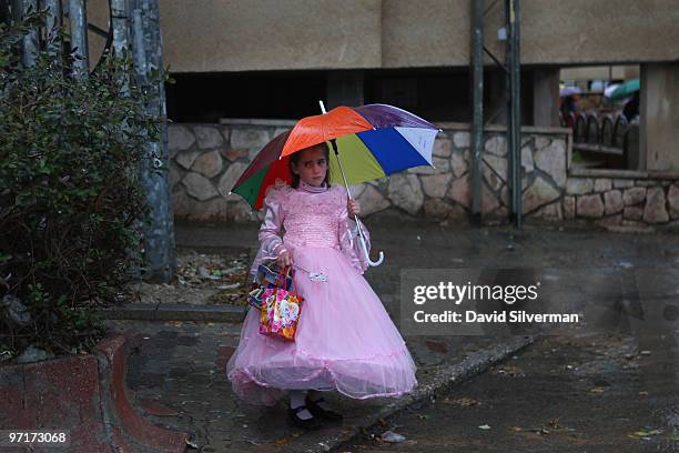 Young ultra-Orthodox Jewish girl wearing her fancy dress waits for the rain to let up to walk to Purim festivities on February 28, 2010 in the...