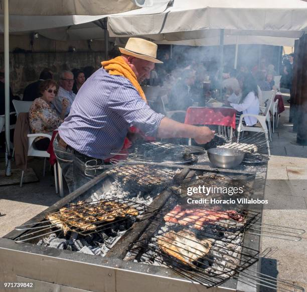Restaurante Alfandega" cook grills sardines, beef and other fish over charcoal by Ave River on May 28, 2018 in Vila do Conde, Portugal. Grilled...