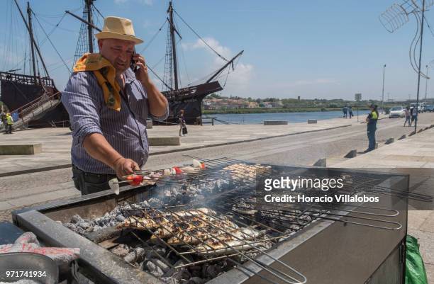 Replica of a Portuguese 16th century caravel is seen behind the "Restaurante Alfandega" cook grilling sardines, beef and other fish over charcoal by...