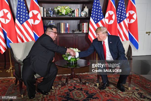 President Donald Trump shakes hands with North Korea's leader Kim Jong Un as they sit down for their historic US-North Korea summit, at the Capella...