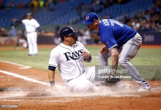 Wilson Ramos of the Tampa Bay Rays slides home safely ahead of pitcher John Axford of the Toronto Blue Jays to score off of a throwing error by...