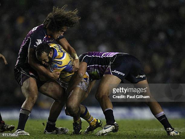 Jamie Jones-Buchanan of Leeds Rhinos is tackled by Kevin Proctor and Adam Blair of Melbourne Storm during the World Club Challenge match between...