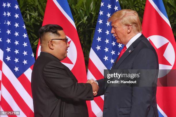 In this handout photo, North Korean leader Kim Jong-un shakes hands with U.S. President Donald Trump during their historic U.S.-DPRK summit at the...