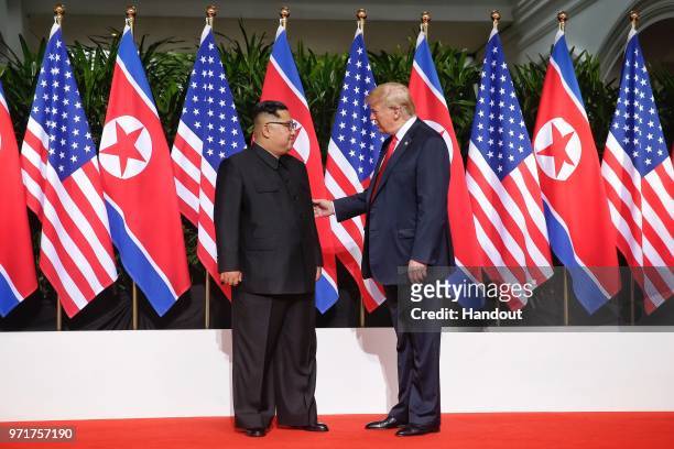 In this handout photo, North Korean leader Kim Jong-un meets U.S. President Donald Trump during their historic U.S.-DPRK summit at the Capella Hotel...