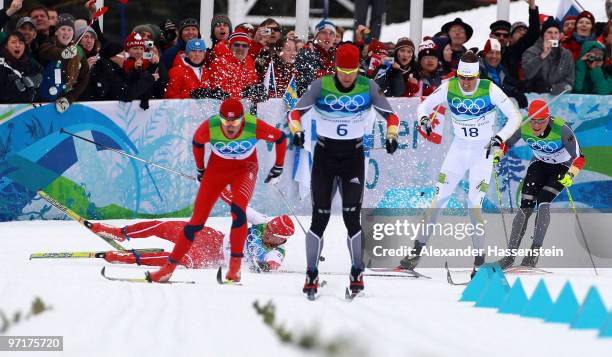 Dario Cologna of Switzerland crashes to the snow as Petter Northug of Norway competes on his way to winning the gold medal from Axel Teichmann of...