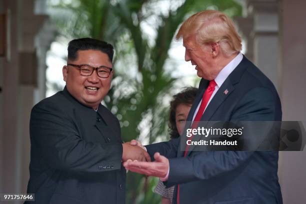In this handout photo, North Korean leader Kim Jong-un shakes hands with U.S. President Donald Trump during their historic U.S.-DPRK summit at the...