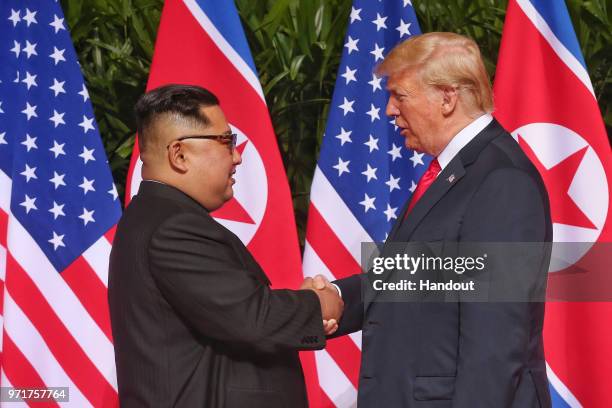 In this handout photo, North Korean leader Kim Jong-un shakes hands with U.S. President Donald Trump during their historic U.S.-DPRK summit at the...