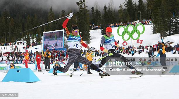 Devon Kershaw of Canada and Tobias Angerer of Germany cross the finish line during the Men's 50 km Mass Start Classic cross-country skiing on day 17...