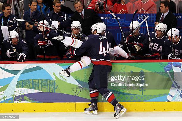 Brooks Orpik of the United States checks a Team Canada member over the boards during the ice hockey men's gold medal game between USA and Canada on...