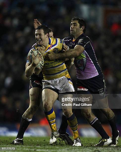 Danny McGuire of Leeds Rhinos is tackled by Cameron Smith and Ryan Hoffman of Melbourne Storm during the World Club Challenge match between Leeds...