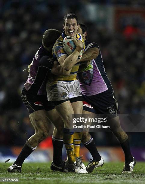 Danny McGuire of Leeds Rhinos is tackled by Cameron Smith and Ryan Hoffman of Melbourne Storm during the World Club Challenge match between Leeds...