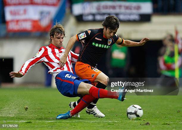 David Silva of Valencia is tackled by Juan Valera of Atletico Madrid during the La Liga match between Atletico Madrid and Valencia at Vicente...