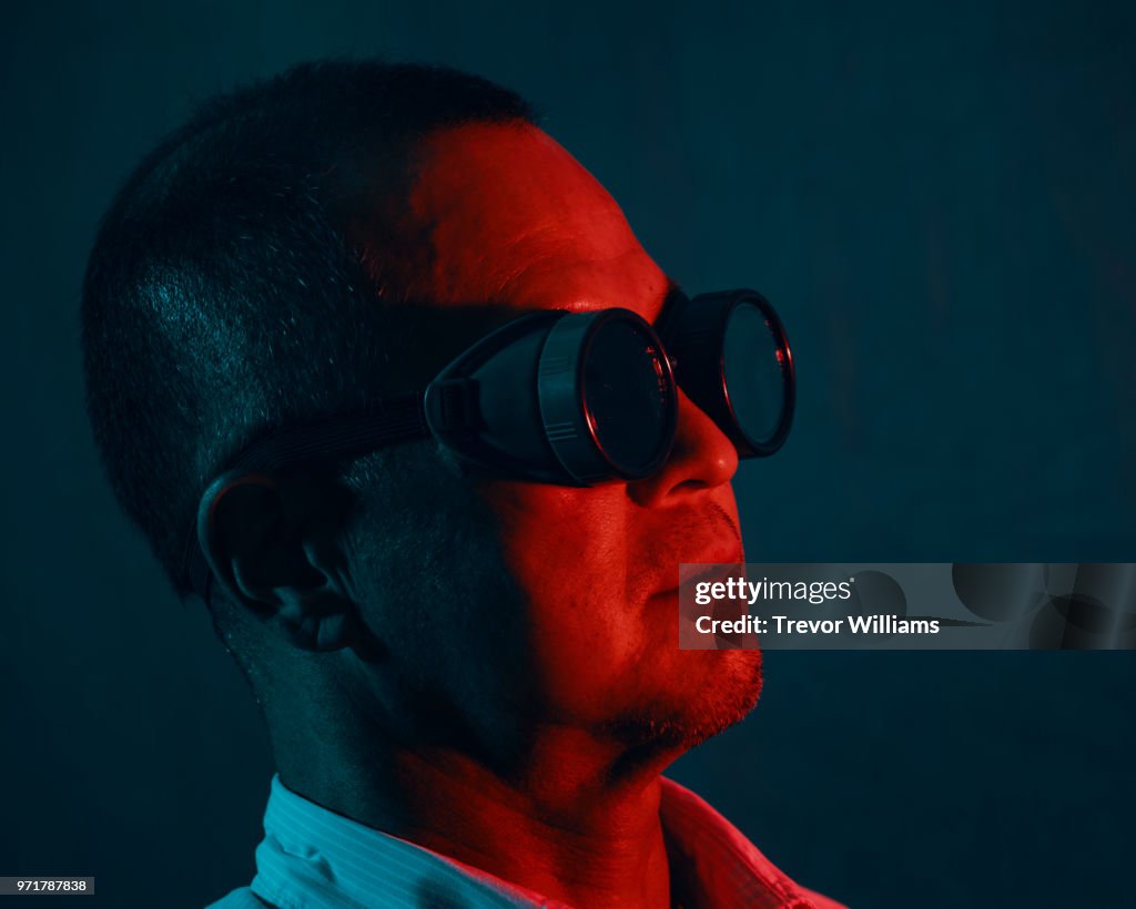 Portrait of a mature man wearing goggles under a red and blue light