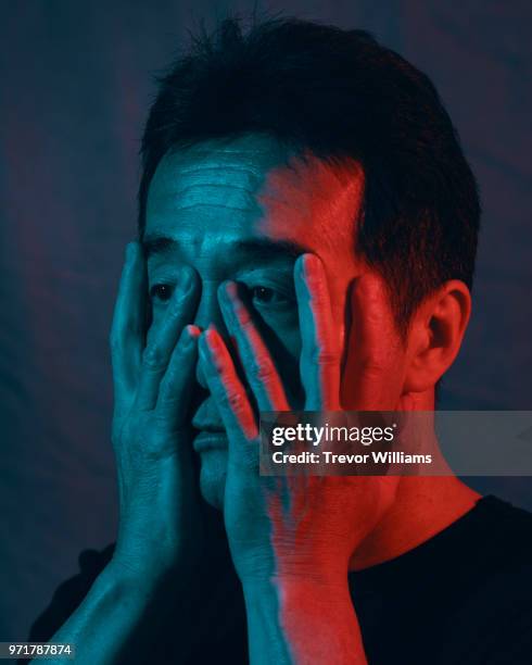 mature man with hands covering face with a worried expression - pain face portrait stockfoto's en -beelden