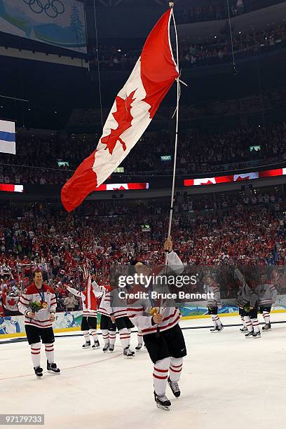 Sidney Crosby of Canada waves a national flag following his team's 3-1 overtime victory during the ice hockey men's gold medal game between USA and...