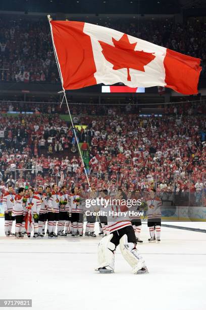 Roberto Luongo of Canada waves his national flag following his team's 3-2 overtime victory during the ice hockey men's gold medal game between USA...