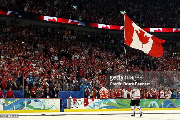 Sidney Crosby of Canada waves a national flag following his team's 3-2 overtime victory during the ice hockey men's gold medal game between USA and...