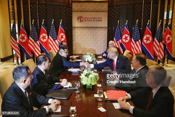 In this handout photo, North Korean leader Kim Jong-un shakes hands with U.S. President Donald Trump during their historic U.S.-DPRK summit at the...