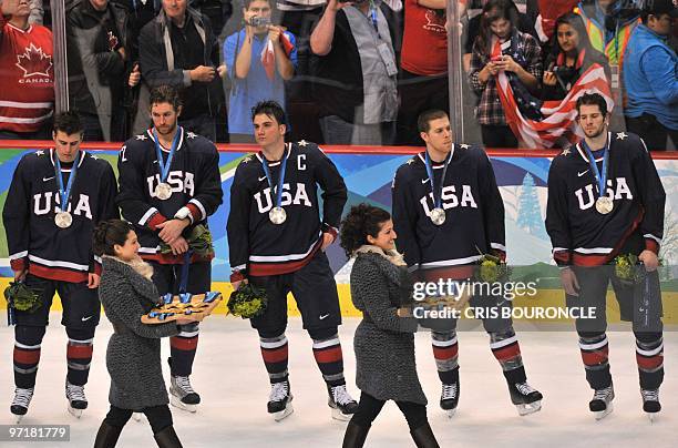 The USA team watch as the gold medals are carried past towards the Canadian team during the medal ceremony in the Men's Gold Medal Hockey match at...