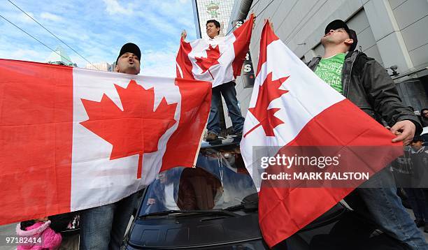 Daniel Dilao waves the Canadian flag from the roof of his car with other fans as they celebrate after Canada defeated the US during the Winter...
