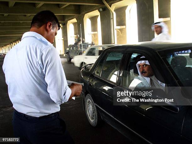 Aug. 8 -- A police officer, left, checks the registration of a luxury car while the passenger looks on. A US military patrol, in background, is on...