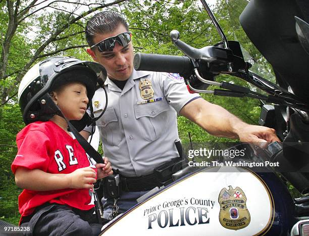 Merlin 5/2/04 amh CREDIT: Larry Morris/TWP NEG NUMBER: 155009 Palmer Park, VA Cpl James Buckles explanes the controls on his motorcycle to 4 year old...