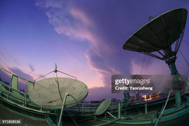 satellite television dish on the building over city bay at twilight sunset,beautiful cloud and monster shape of cloud due to the typhoon coming - satellite dish foto e immagini stock