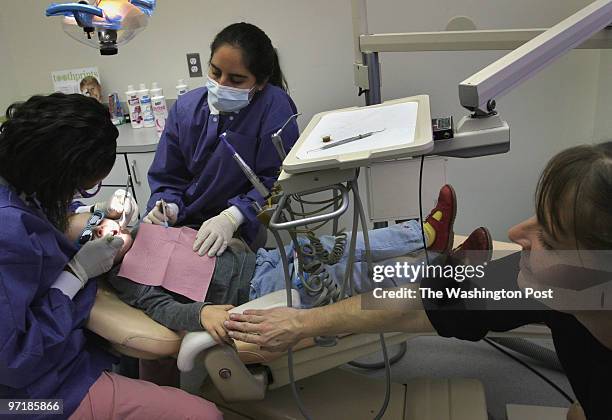 First time at the dentist: Audrey Hansen, 3 years old, has her hand held my mom Nina Smith while dental hygenist Adrian Parker examines her teeth and...