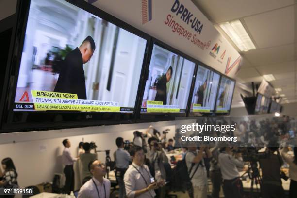 Members of the media watch as television screens display a news broadcast of North Korean leader Kim Jong Un arriving for a summit with U.S....